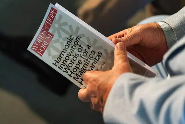 Le mani di un partecipante con il libretto del forum