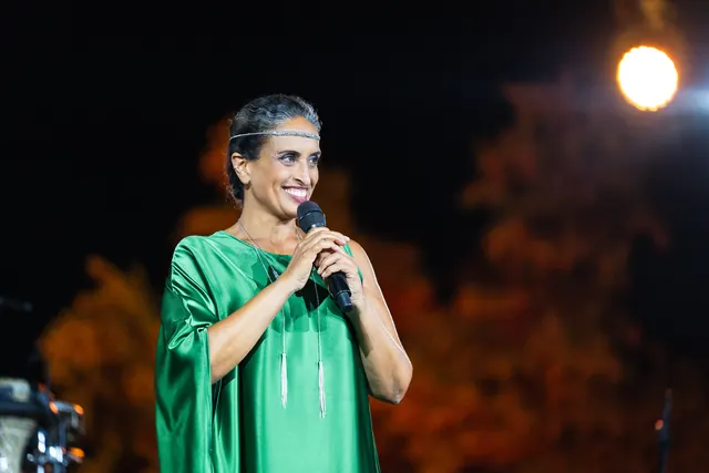 Noa nell'abito verde, sorridente, con il microfono